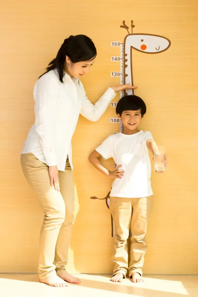 A young mother is measuring her son's height at home. its measure on device which convert 150 cm to feet